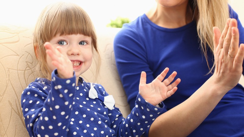 Mutter und Tochter singen und klatschen zu Kinderreimen