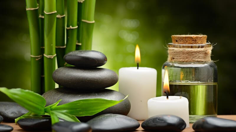 Spa und Wellness: schwarze Steine, weiße Kerzen, Bambus und Massageöl