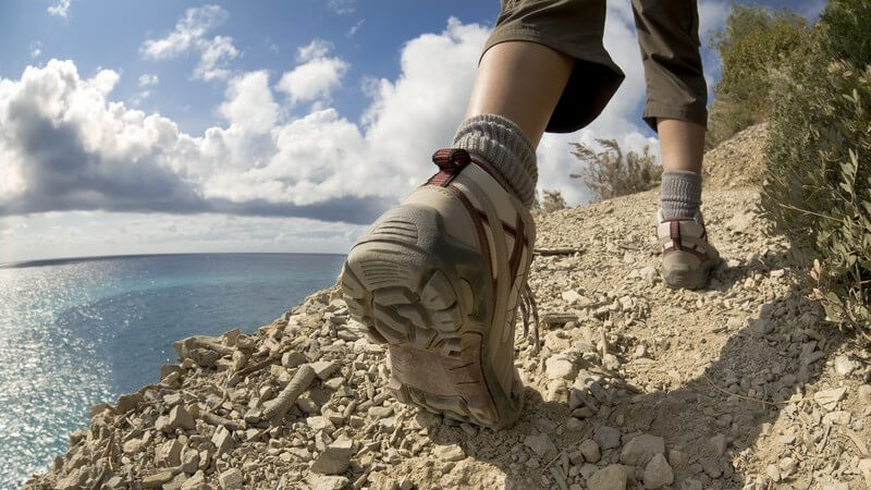 Frauenfüße mit Wanderschuhen wandern auf Klippe am Meer