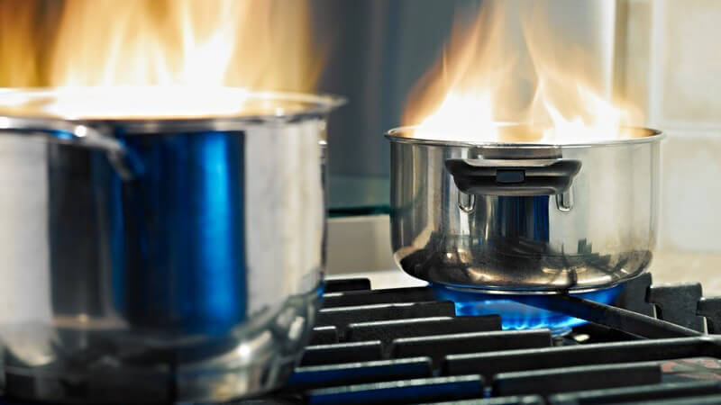 Zwei Töpfe in Flammen auf einem Gasherd