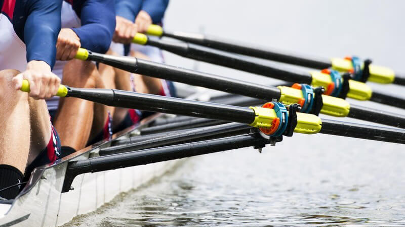 Nahaufnahme männliches Ruderteam im Boot im Wasser