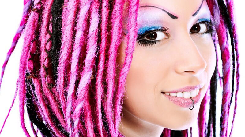 Gesichtsportrait junge Frau mit Labret Piercing und pinken Dreads