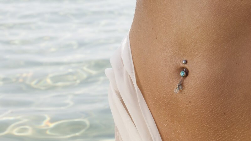 Ausschnitt nackter Frauenkörper, Piercing im Bauchnabel