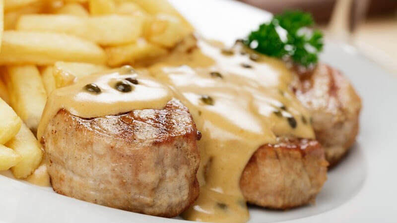 Teller mit Schweinemedaillons mit Pfeffersauce und Pommes frites