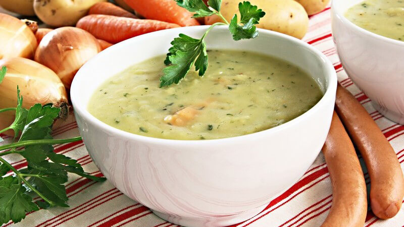 Kartoffelsuppe in Schale mit Bockwürstchen auf Tisch
