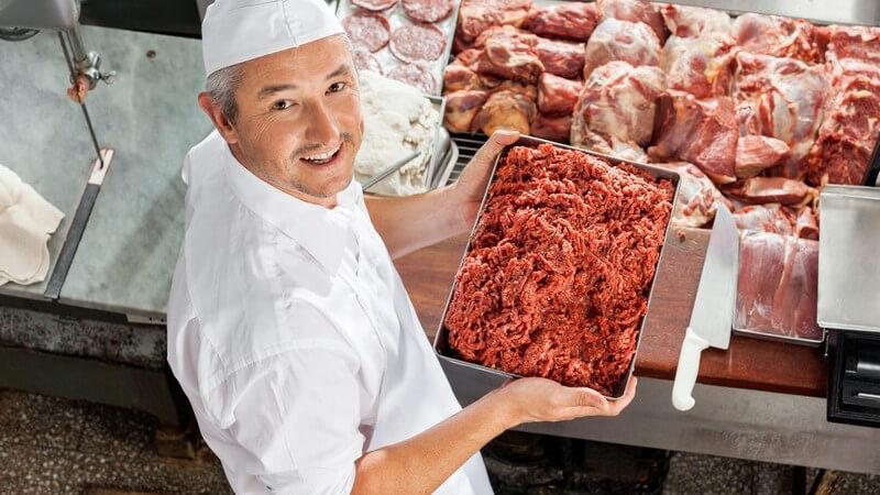 Metzger hält eine große Schale mit frischem Hackfleisch