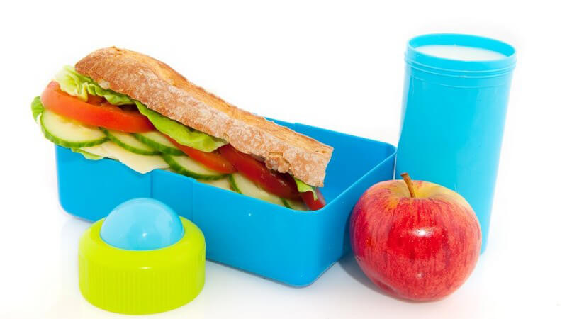 Lunchbox mit Baguette, Apfel, Becher mit Milch