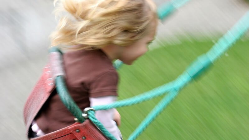 Kleines Mädchen schaukelt draußen auf Schaukel