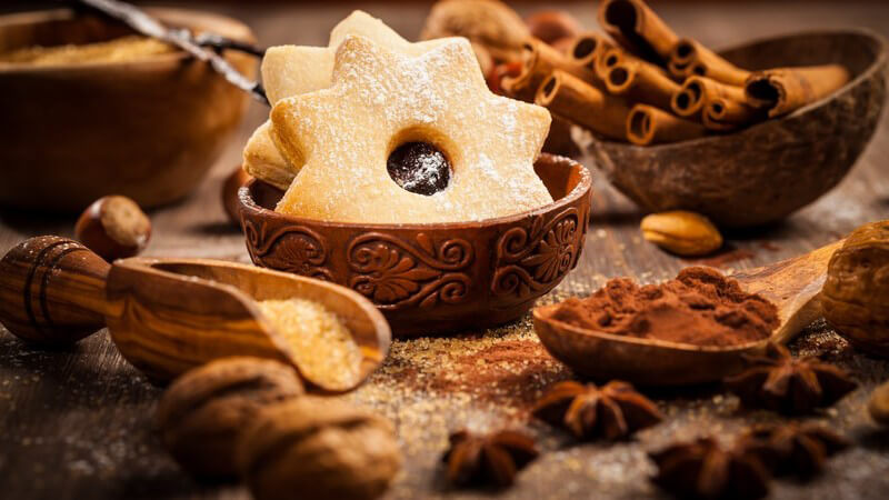 Sternförmige Weihnachtsplätzchen umgeben von Backzutaten und Gewürzen für Weihnachtsgebäck