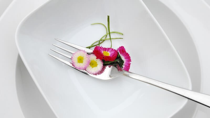 Gabel mit Gänseblümchen auf weißem Teller