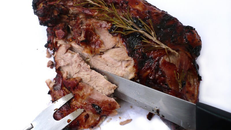 Fleischbraten wird mit Gabel gehalten und mit Messer geschnitten