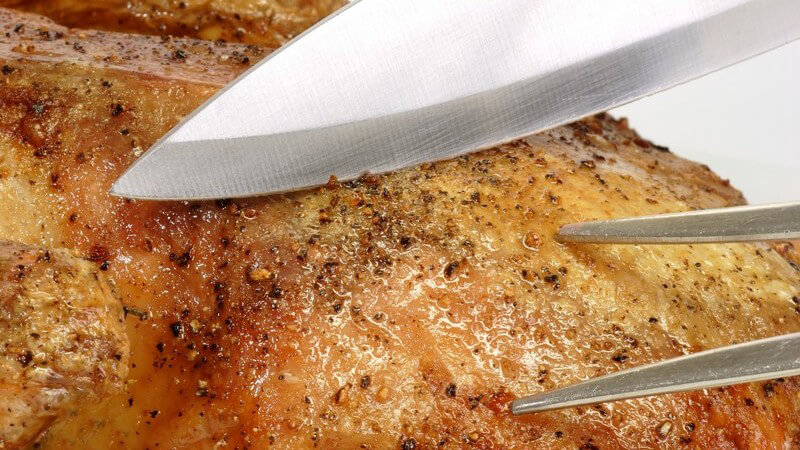 Nahaufnahme fertiger Braten, Fleischgabel und Messer werden daran gehalten