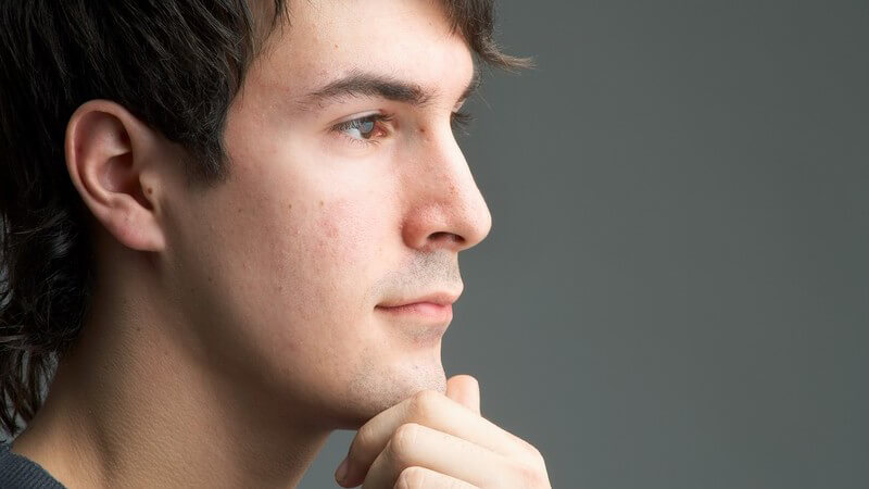 Seitenansicht Gesichtsportrait junger Mann, Hand an Kinn gelegt