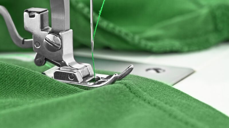 Nähmaschine beim Nähen von grünem Stoff mit grünem Faden