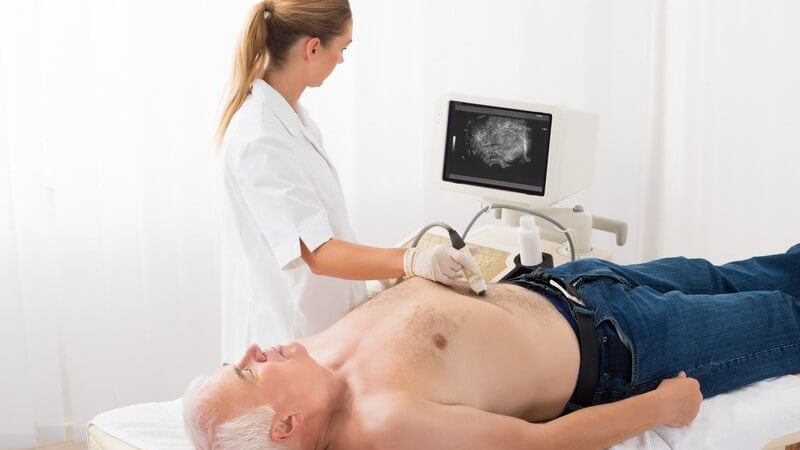 Ärztin führt bei einem älteren Mann eine Ultraschalluntersuchung im Bauchbereich durch