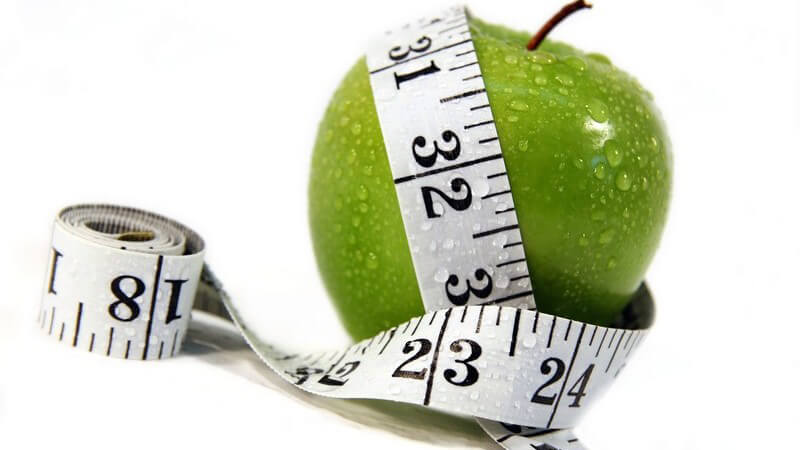 Frischer grüner Apfel, gerade gewaschen, Maßband darum gelegt