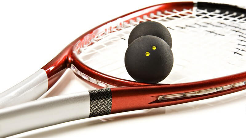 Squashschläger und Squashbälle auf weißem Untergrund