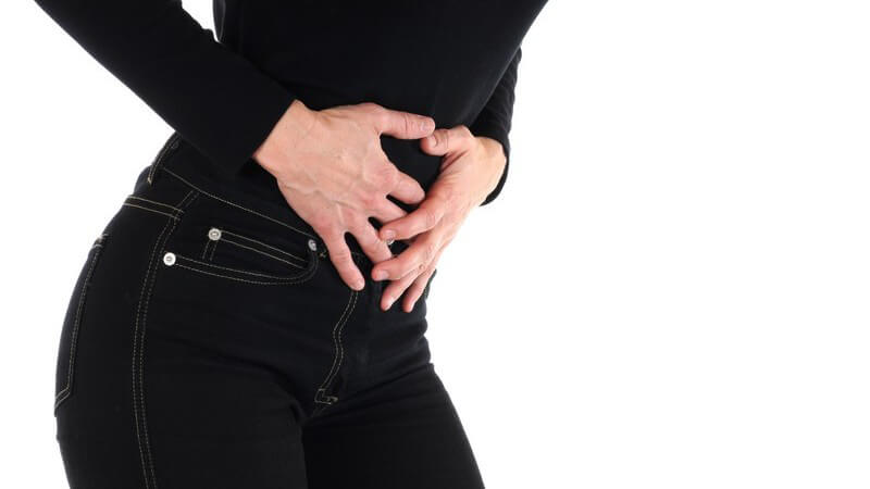 Frauenhände auf Bauch gelegt, schwarze Jeans und schwarzes Oberteil