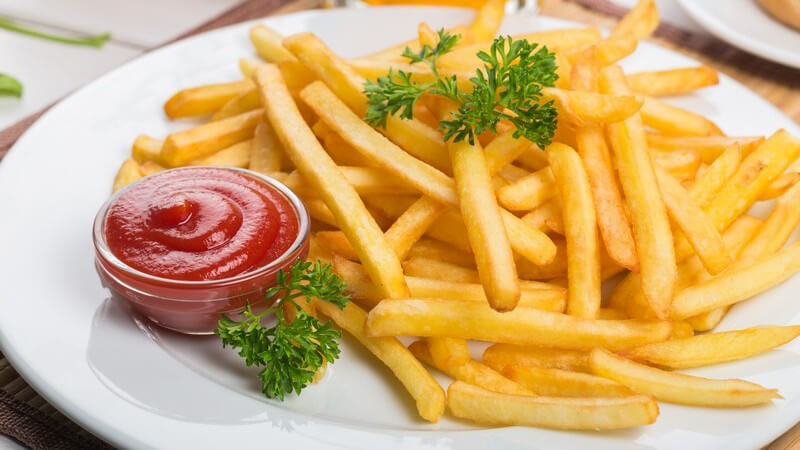 Portion Pommes auf Teller, mit Ketchup in Glasschüsselchen