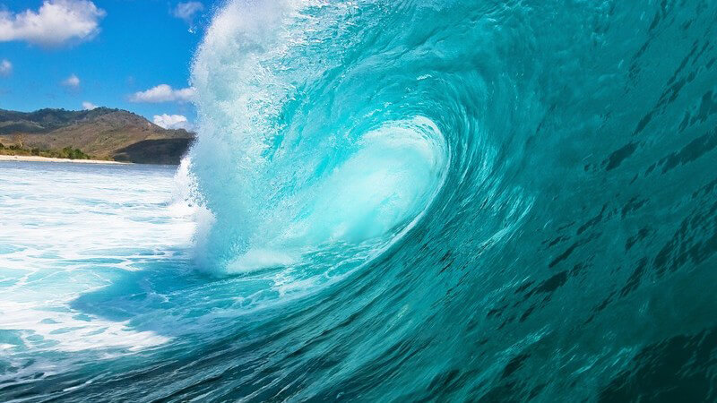 Seitliche Aufnahme, Welle im türkisen Meer kommt aufs Land zu