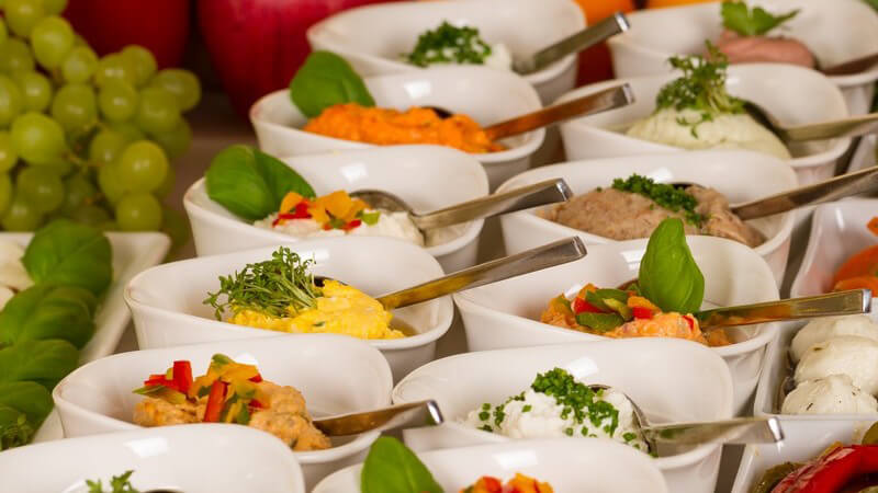 Catering: Buffetplatte mit vielen kleine Schälchen mit Dips, garniert mit Basilikum