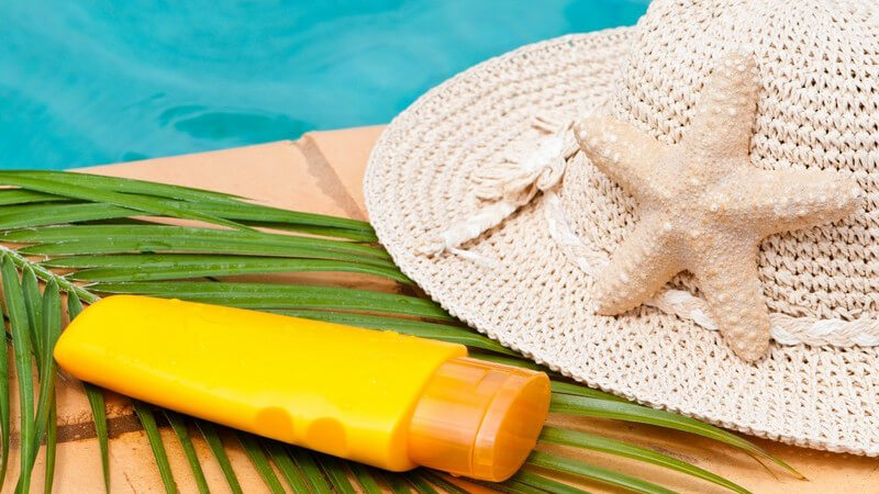 Sonnenhut, -creme und Palmenblatt an Pool