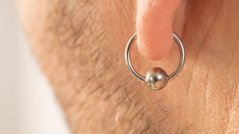 Nahaufnahme eines Männerohrs mit Piercingring am Ohrläppchen