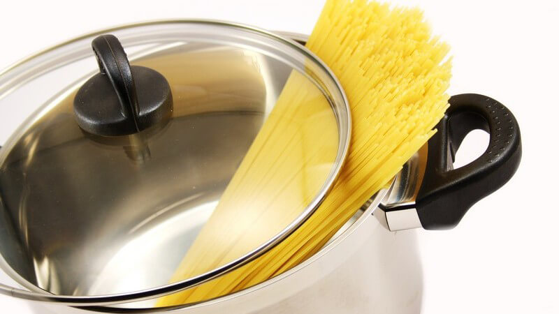 Spaghetti liegen in Kochtopf, darüber Deckel