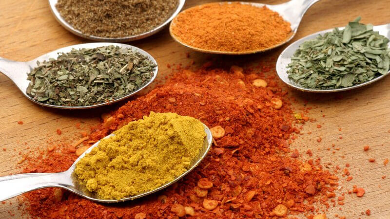 Verschiedene Gewürzpulver wie Curry, Chili auf Löffeln
