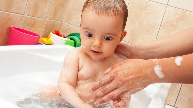 Säugling wird von Mutter in Badewanne gebadet