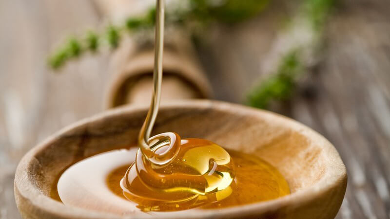 Nahaufnahme Honig wird auf Holzlöffel gegossen