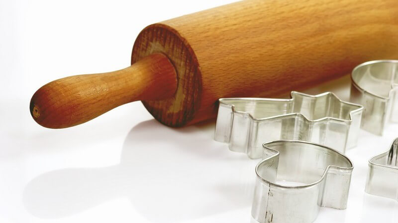 Nudelholz neben Ausstechformen für Plätzchen auf weißem Hintergrund