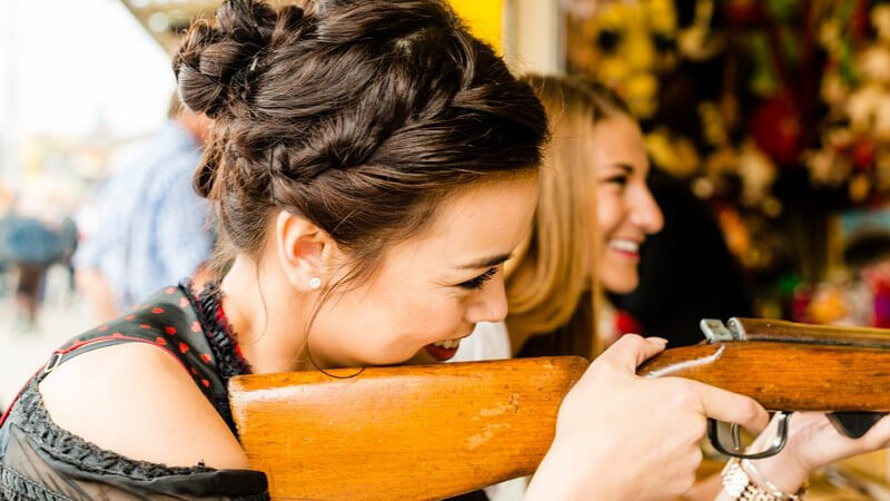 Zwei junge Frauen an haben Spaß an einer Schießbude auf dem Jahrmarkt