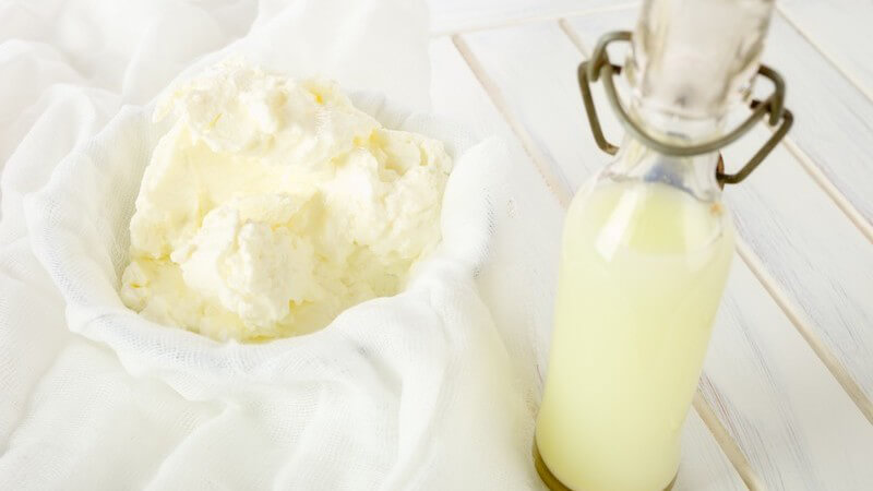 Selbstgemachter Quark neben Fläschchen mit Molke