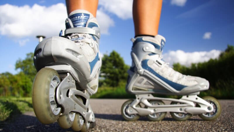 Nahaufnahme Inline Skates auf Asphalt, blauer Himmel