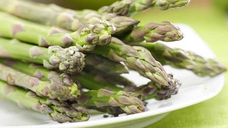 Nahaufnahme grüner Spargel auf weißem Teller
