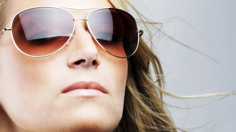 Junge Frau mit riesiger Sonnenbrille und wehendem Haar