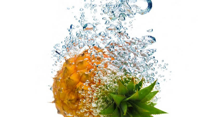 Ananas fällt ins Wasser und hinterlässt Wasserblasen unter Oberfläche
