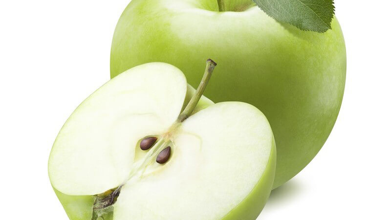 Ganzer und halbierter grüner Apfel vor weißem Hintergrund