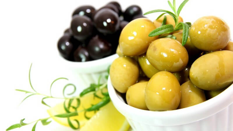 Grüne und schwarze Oliven in weißer Schale