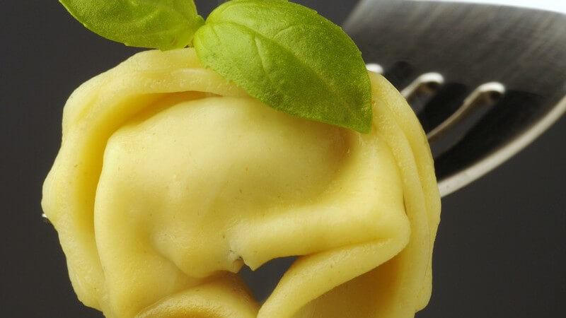 Nahaufnahme Tortellini mit Basilikum auf Gabel