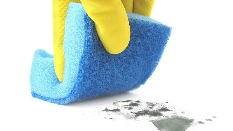 Nahaufnahme Hand in gelbem Gummihandschuh wischt mit türkisem Schwamm Schmutz weg