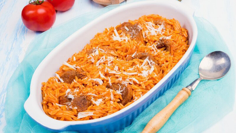 Griechischer Nudelauflauf mit Kritharaki und Fleisch, Auflaufform auf blauem Deckchen