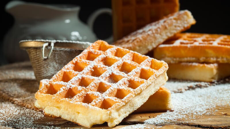 Belgische Waffeln mit Puderzucker auf altem Holztisch