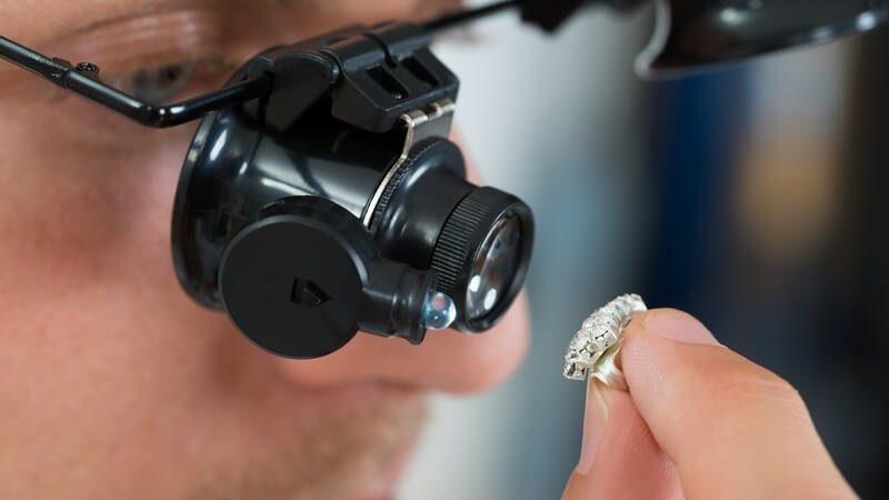 Juwelier untersucht einen Diamantring durch eine Lupenbrille