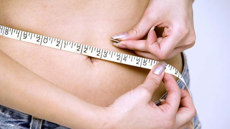 Frau misst mit Maßband ihren Bauchumfang