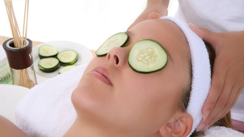 Junge Frau mit Gurkenscheiben auf Augen bekommt Kopfmassage