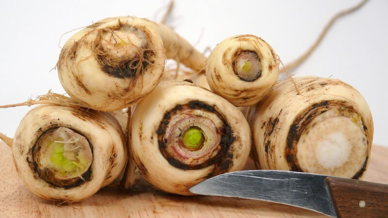 Pastinaken auf Holzbrette, daneben Messer