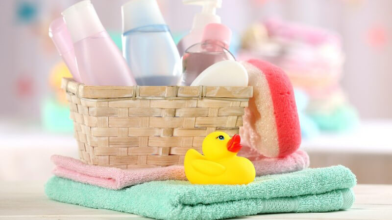 Utensilien für ein Babybad wie Badeente, Handtücher, Schwamm und Shampoo