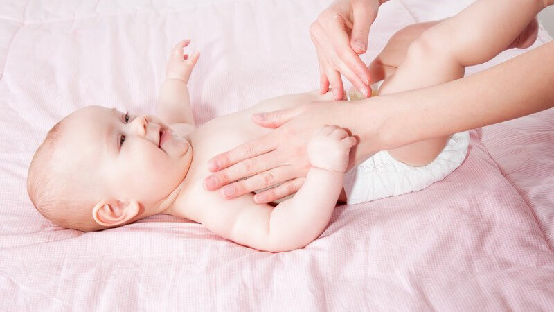 Mutter streichelt ihren Säugling auf einem rosa Wickeltisch